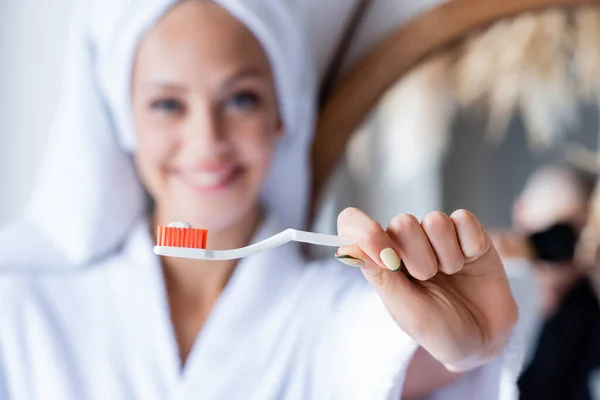 Femme floue et joyeuse tenant une brosse à dents avec du dentifrice — Photo de stock