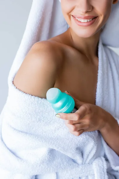 Cropped view of happy young woman holding deodorant roll on in bathroom — Stock Photo