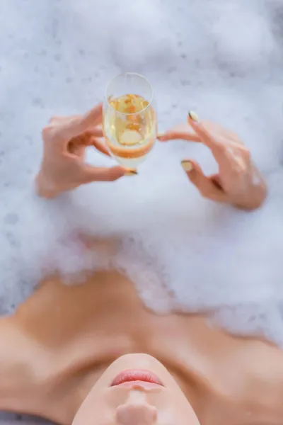 Vue recadrée de la femme prenant un bain et tenant une coupe de champagne — Photo de stock