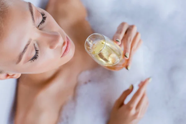 Vue de dessus de la femme prenant un bain et tenant une coupe de champagne — Photo de stock