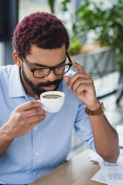 Uomo d'affari afroamericano in occhiali con in mano una tazza di caffè in carica — Foto stock