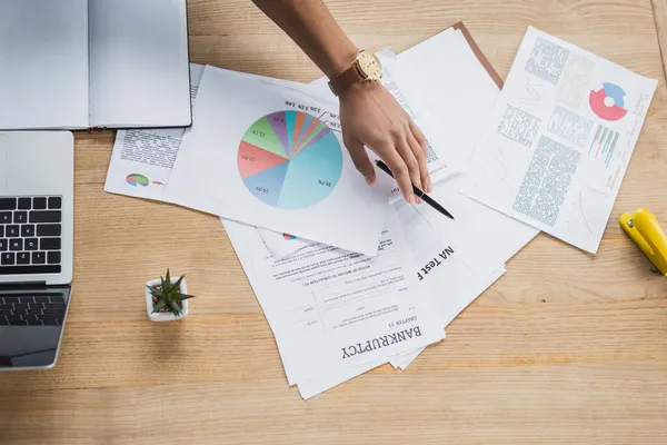 Vista dall'alto del manager afroamericano che tiene la penna vicino a documenti, laptop e notebook in ufficio — Foto stock