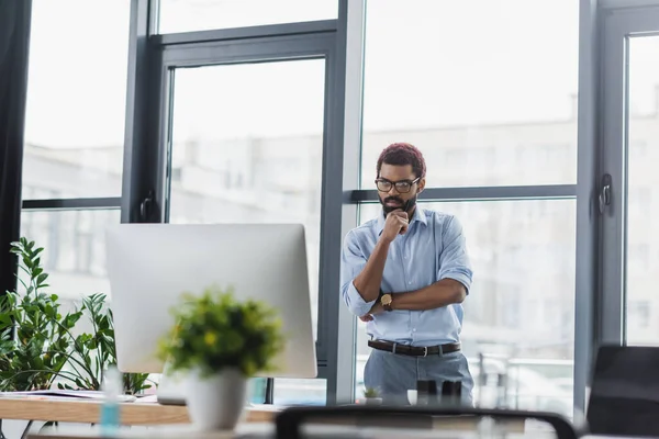 Konzentrierter afrikanisch-amerikanischer Geschäftsmann blickt im Büro auf Computermonitor — Stockfoto