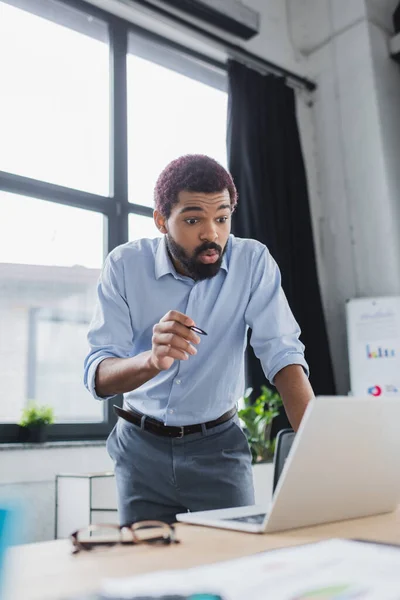 Junger afrikanisch-amerikanischer Geschäftsmann zeigt bei Videoanruf im Büro auf Laptop — Stockfoto