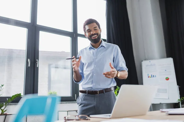 Positive african american businessman having video chat on laptop in office — Stock Photo