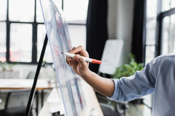 Ausgeschnittene Ansicht eines afrikanisch-amerikanischen Geschäftsmannes, der im Büro auf Glastafel schreibt — Stockfoto