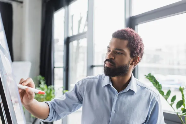 African american manager writing on glass board in office — Stock Photo