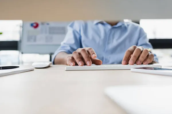 Vista cortada do empresário afrcan americano usando o computador perto do smartphone na mesa — Fotografia de Stock