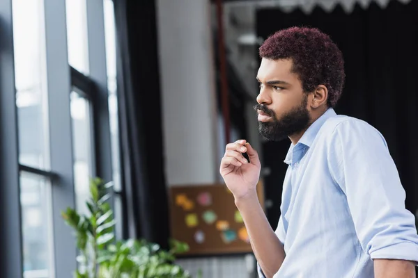 Junger afrikanisch-amerikanischer Geschäftsmann schaut im Büro weg — Stockfoto