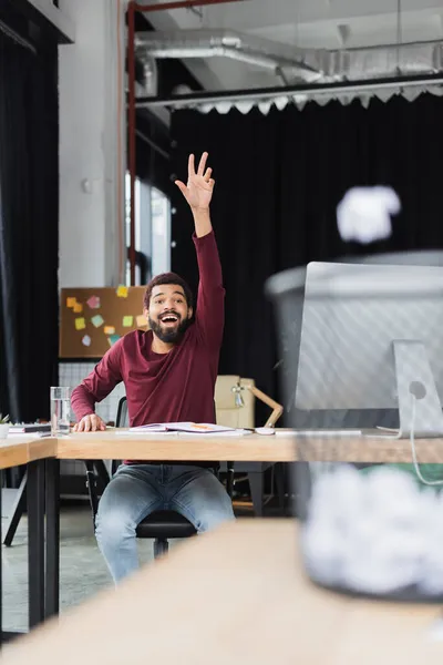 Excited african american businessman throwing crumpled paper in blurred trash can in office — Stock Photo