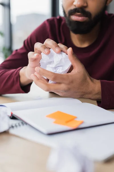 Vue recadrée d'un homme d'affaires afro-américain froisser du papier près d'un ordinateur portable au bureau — Photo de stock