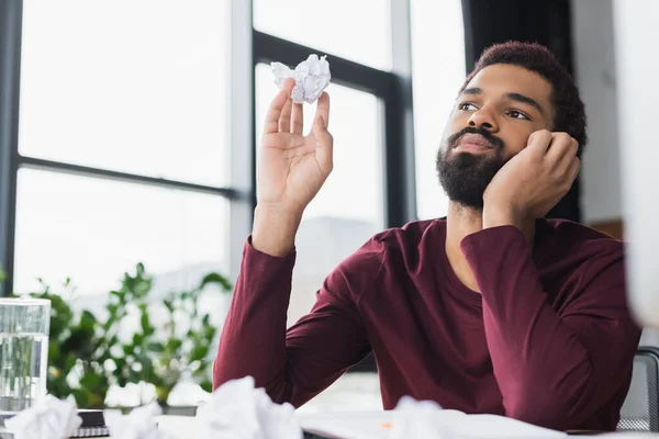 Homme d'affaires afro-américain en vêtements décontractés tenant du papier froissé au bureau — Photo de stock