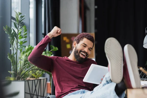 Aufgeregter afrikanisch-amerikanischer Geschäftsmann zeigt Ja-Geste mit digitalem Tablet im Büro — Stockfoto