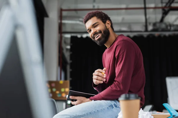 Empresário afro-americano segurando caderno e olhando para a câmera no escritório — Fotografia de Stock