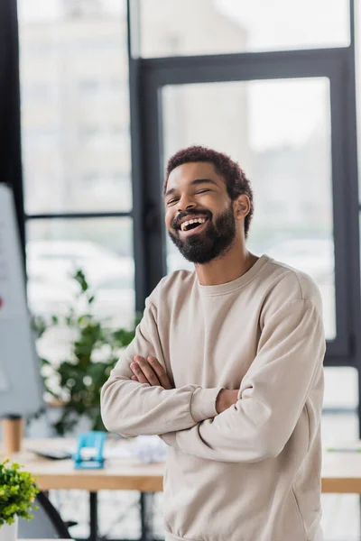 Glücklicher afrikanisch-amerikanischer Geschäftsmann blickt im Büro in die Kamera — Stockfoto