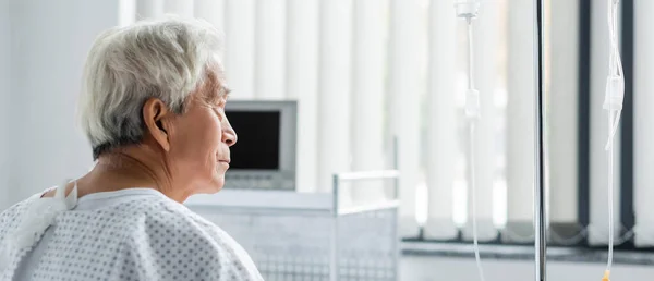 Seitenansicht einer Seniorin im Kleid, die sich die intravenöse Therapie auf der Krankenhausstation ansieht, Banner — Stockfoto