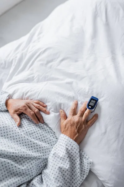 Vue du dessus du patient âgé avec oxymètre de pouls sur lit d'hôpital — Photo de stock