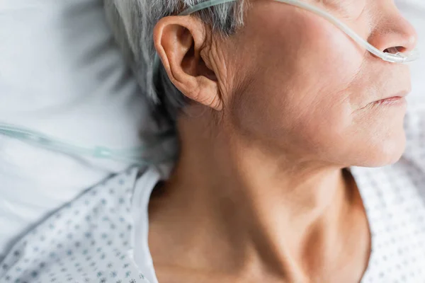 Ausschnitt eines älteren Patienten mit Nasenkanüle, der im Krankenhaus auf dem Bett liegt — Stockfoto