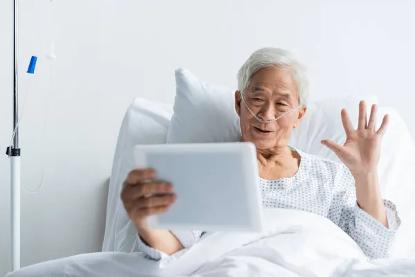 Senior paziente asiatico con cannula nasale avere videochiamata su tablet digitale in clinica — Foto stock
