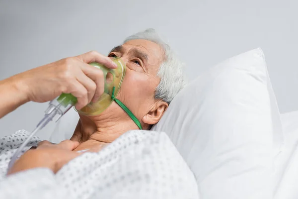 Elderly asian patient breathing in oxygen mask on bed in clinic — Stock Photo