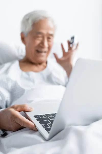 Laptop near blurred asian patient having video call in hospital ward — Stock Photo