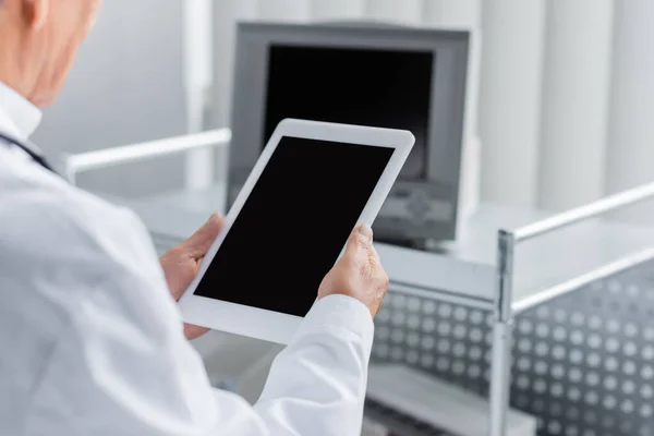 Vista recortada de médico desfocado segurando comprimido digital com tela em branco no hospital — Fotografia de Stock