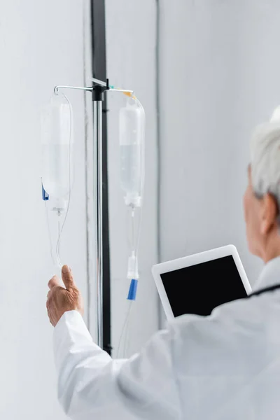 Intravenöse Therapiestation bei verschwommenem Arzt mit digitalem Tablet im Krankenhaus — Stockfoto
