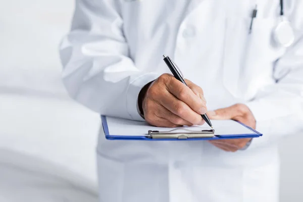 Ausgeschnittene Ansicht des Arztes beim Schreiben auf Klemmbrett in der Klinik — Stockfoto