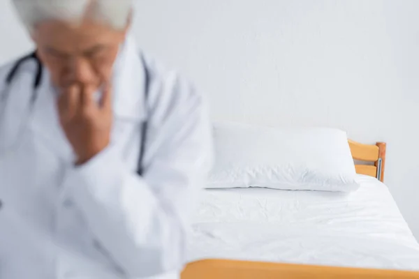 Cama cerca de médico borroso en la sala de hospital - foto de stock