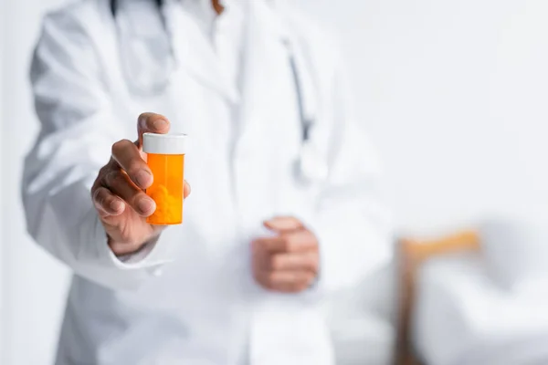 Cropped view of blurred doctor holding pills in hospital — Stock Photo