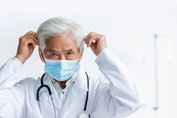 Senior asiatico medico indossare medico maschera in clinica — Foto stock