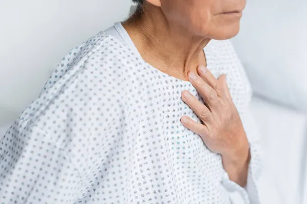 Vista cortada do paciente sênior em vestido tocando no peito na enfermaria do hospital — Fotografia de Stock