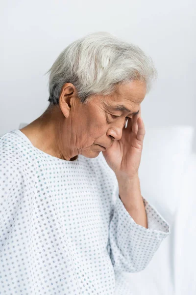 Upset senior asian patient in gown in hospital ward — Stock Photo