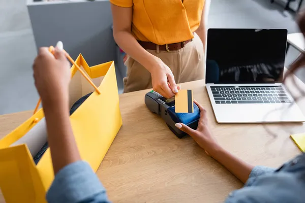 Vista ritagliata del cliente che paga con carta di credito vicino alla commessa americana africana in boutique — Foto stock