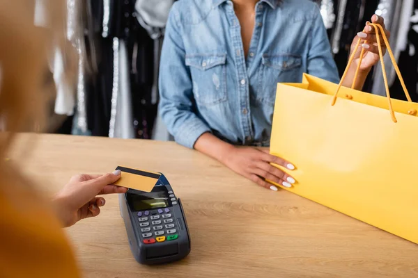 Vista recortada del cliente pagando con tarjeta de crédito en boutique - foto de stock