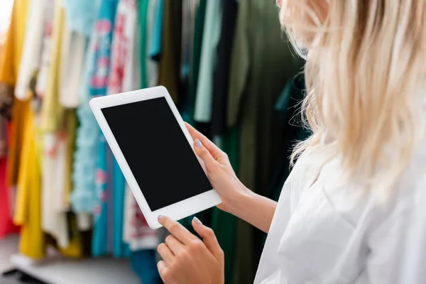 Vista recortada de rubia asistente de ventas en camisa blanca sosteniendo tableta digital en boutique de ropa - foto de stock