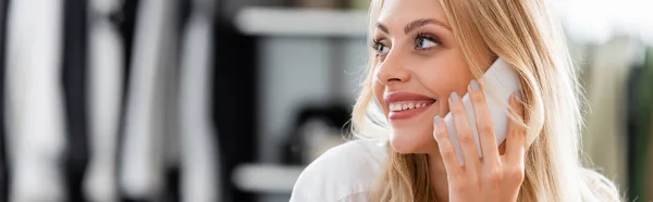 Happy saleswoman talking on smartphone in boutique, banner — Stock Photo