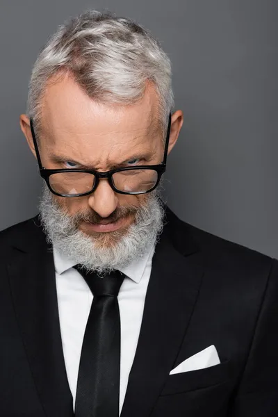 Sérieux homme d'affaires d'âge moyen dans des lunettes regardant caméra isolé sur gris — Photo de stock