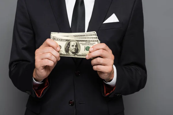 Обрізаний вид середнього віку бізнесмен тримає доларові банкноти ізольовані на сірому — стокове фото