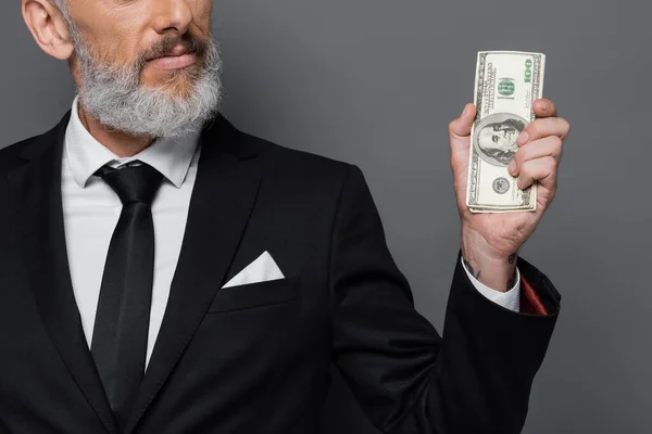 Cropped view of tattooed middle aged businessman holding dollar banknotes isolated on grey — Stock Photo