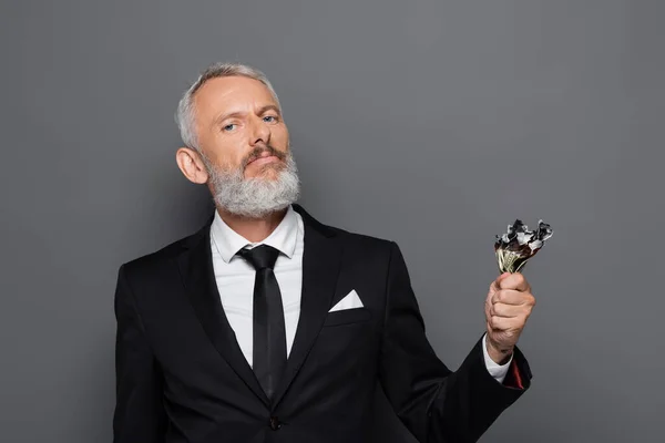 Bearded middle aged businessman holding burning dollar banknotes isolated on grey — Stock Photo