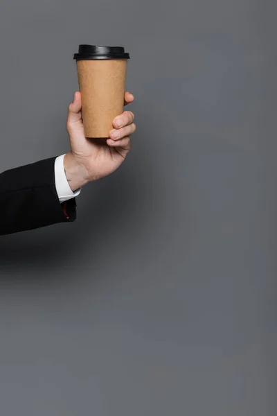 Vue recadrée de l'homme d'affaires tenant tasse en papier sur gris — Photo de stock