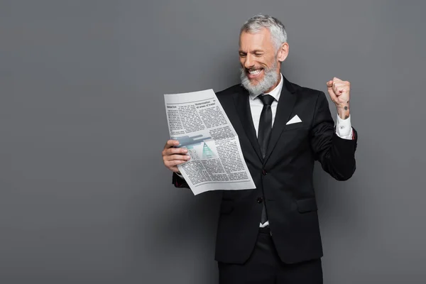 Heureux homme d'affaires d'âge moyen lecture journal sur gris — Photo de stock