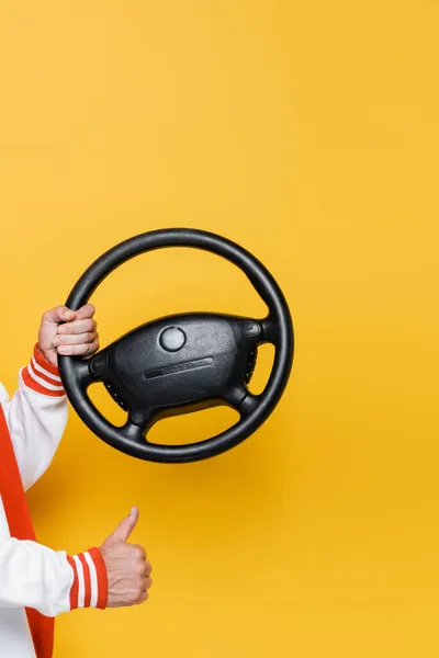 Cropped view of middle aged man holding steering wheel and showing like on yellow — Stock Photo