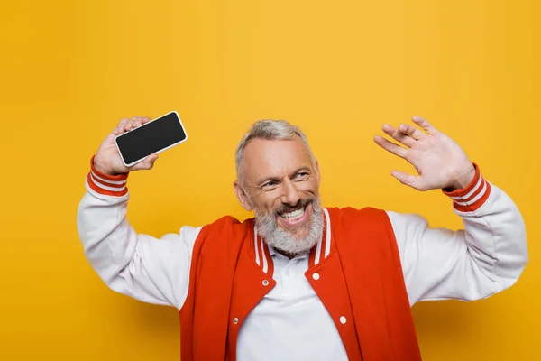 Hombre de mediana edad positivo sosteniendo el teléfono celular con pantalla en blanco en amarillo - foto de stock