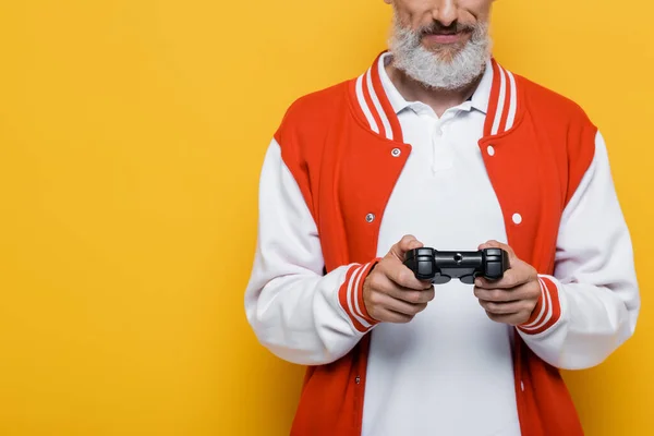 KYIV, UKRAINE - JULY 29, 2021: cropped view of middle aged man in bomber jacket holding joystick on yellow — Stock Photo