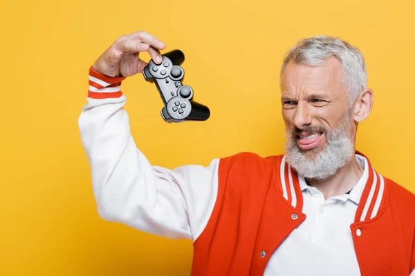 KYIV, UKRAINE - 29 JUILLET 2021 : homme d'âge moyen mécontent en blouson de bombardier tenant un joystick isolé sur jaune — Stock Photo