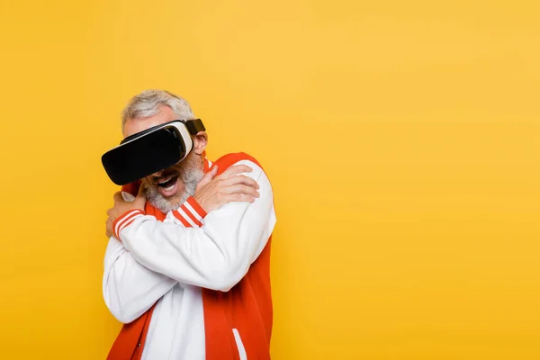 Scared middle aged man in bomber jacket and vr headset isolated on yellow — Stock Photo