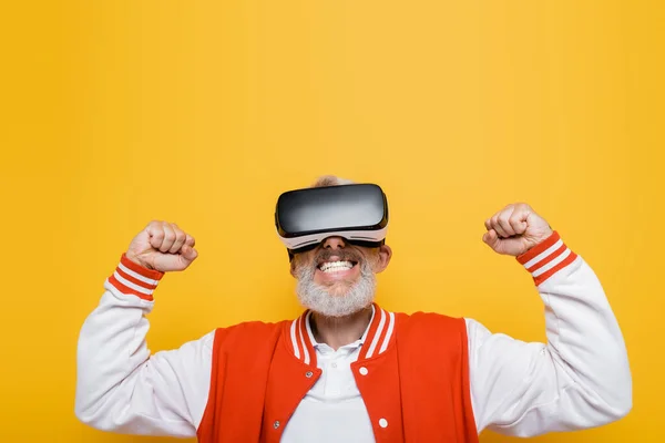 Middle aged man in bomber jacket and vr headset rejoicing isolated on yellow — Stock Photo