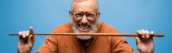 Sorridente insegnante di mezza età in bicchieri tenendo bastone puntatore isolato su blu, banner — Foto stock